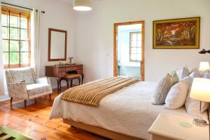 a bedroom with a bed and a desk and a chair at Burnside Lodge in Balgowan