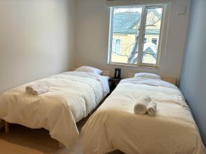 two twin beds in a room with a window at ニセコ泉居アパートメント in Kutchan