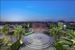 a large courtyard with palm trees and a building at favehotel Madiun in Madiun