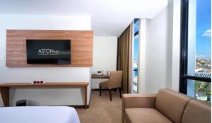 a hotel room with a bed and a desk with a tv at Aston Inn Pandanaran in Semarang