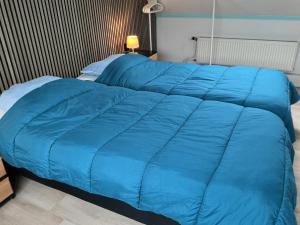 a blue comforter on a bed in a room at Zomerhuis Zwart in Egmond aan Zee