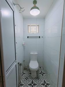 a white bathroom with a toilet and a window at Desa Ibol Cottage and River - Max 10Pax in Kampong Sumpitan