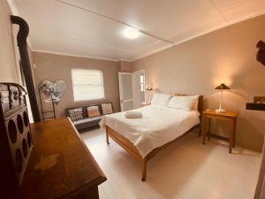 a bedroom with a bed and a table and a couch at Joan's Sea Cottage in Pringle Bay +23 photos