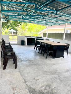 a patio with a table and chairs under a roof at Desa Ibol Cottage and River - Max 10Pax in Kampong Sumpitan +15 photos