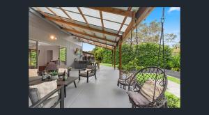a patio with chairs and tables and a roof at Between Trees and Tide in Torquay