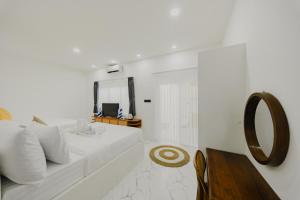 a white bedroom with a white couch and a mirror at Ayodhya Villa Utari - North Wings in Yogyakarta