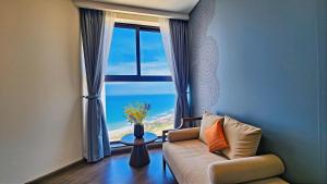 a living room with a couch and a large window at Mandala Sands Mũi Né in Phan Thiet