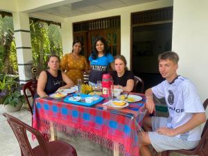 a group of people sitting around a table with food at Samson's Home in Hiriketiya +15 photos