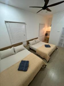 two beds in a room with a ceiling fan at Desa Ibol Cottage and River - Max 10Pax in Kampong Sumpitan