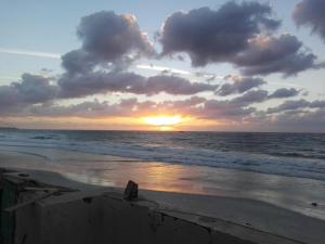 a sunset on the beach with the ocean at On the Beach Villa Apartment in Alexandria
