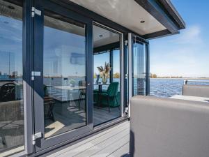a balcony with glass doors and a table on a boat at Houseboat Uitgeest with Air Conditioning | 4 people in Uitgeest