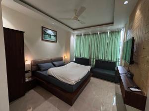 a bedroom with a bed and a couch and a television at Hotel Buransh in Haldwāni +23 photos