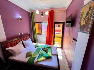 a bedroom with a bed with purple walls and a window at NGK Hôtel Apartment in Bafoussam