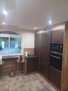 a kitchen with a desk and a microwave and a window at Magnifique villa avec piscine 10x5 m sur 1800m2 de terrain avec parking privatif cuisine recente equpee 3 chambres dont 2 parental au rdc avec wc separe pas de vis à vis terrain de petanque bbq climatisation jeux enfants in Sérignan