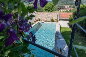 a swimming pool in a garden with purple flowers at A l'Ombre du Château in Nans-sous-Sainte-Anne