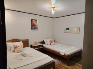 two beds in a room with white walls at EL3 Z'sPLACE HOSTEL in San Vicente