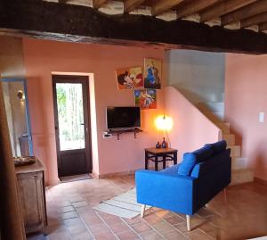 a living room with a blue couch and a tv at Clos Baroanni - Gîte Terra in Terraube