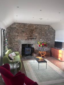a living room with a stone wall with a fireplace at Calsie Cottage, Clatt in Kirktown of Clatt