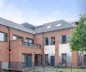 a large brick building with a black roof at Astral Court Premium Accomodation in Ruislip