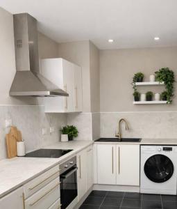a white kitchen with a sink and a dishwasher at Astral Court Premium Accomodation in Ruislip