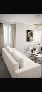 a white living room with a white couch and chairs at Astral Court Premium Accomodation in Ruislip