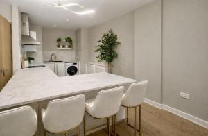 a kitchen with a white counter and white chairs at Astral Court Premium Accomodation in Ruislip