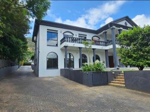 a white house with a balcony on a street at Namloom Guesthouse in Pretoria +12 photos