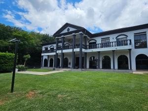 a large white building with a green yard at Namloom Guesthouse in Pretoria