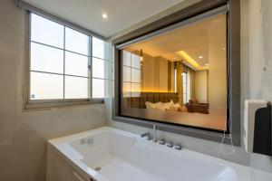 a bathroom with a white tub and a large mirror at The Delhi Dreams - A Luxury Hotel in New Delhi