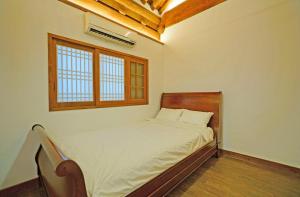 a bedroom with a bed with a wooden headboard and a window at Jeonju Hanok Agbae in Jeonju
