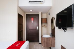 a room with a bed and a tv and a bathroom at RedDoorz @ Wiyung 2 in Kedurus