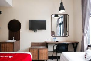 a bedroom with a desk with a tv and a mirror at RedDoorz @ Wiyung 2 in Kedurus +36 photos