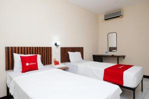 two beds in a hotel room with red pillows at RedDoorz @ Wiyung 2 in Kedurus