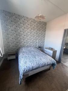 a bedroom with a bed and a patterned wall at JCFORTMAHON in Fort-Mahon-Plage