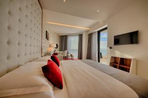 a bedroom with a large white bed with red pillows at Kalamper Hotel & Spa in Dobra Voda