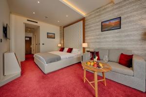 a bedroom with a bed and a couch and a table at Kalamper Hotel & Spa in Dobra Voda +41 photos