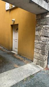a yellow building with a white door and a stone wall at Gite Camélia in La Réorthe