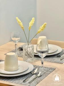 a table with plates and glasses and a vase with flowers at Solace - 1BR Brenthill Condo with Balcony Near Session and SM in Baguio