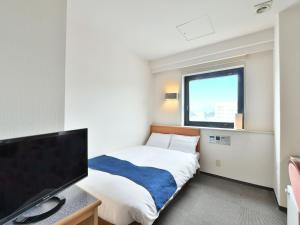 a bedroom with a bed and a flat screen tv at First Inn Haiki in Sasebo
