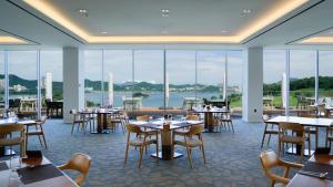 a restaurant with tables and chairs and large windows at Sagewood Yeosu Gyeongdo Resort in Kyŏngho-dong