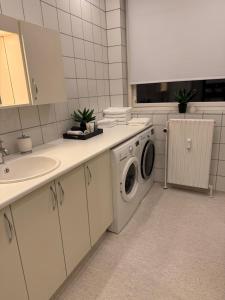 a kitchen with a washing machine and a sink at Lille Vedelsborg in Vejle