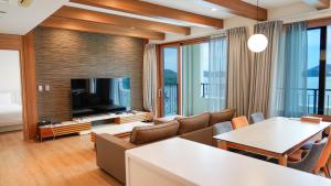 a living room with a couch and a television at Sagewood Yeosu Gyeongdo Resort in Kyŏngho-dong