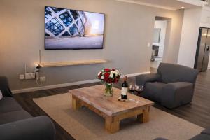 a living room with a bottle of wine and flowers on a table at Van Temp Beach House in Britannia Bay