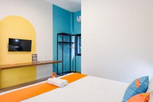 a bedroom with a bed and a tv on a wall at Sans Salmas Mojokerto in Kranggan