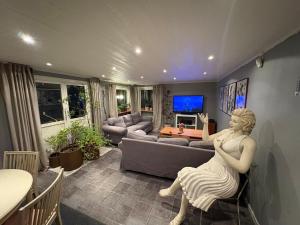 a living room with a statue of a woman sitting in a chair at Blomstergården in Vilshult