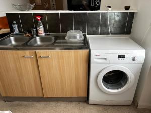 a kitchen with a sink and a washing machine at Gite Camélia in La Réorthe