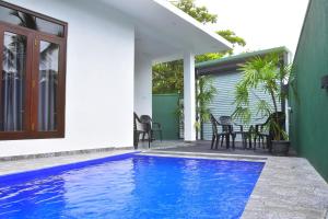 a swimming pool in front of a house at Ceylon Relax Villa in Aluthgama