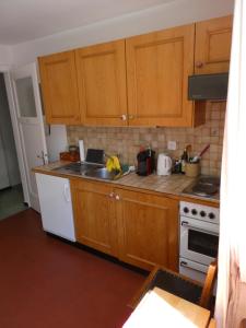 a kitchen with wooden cabinets and a white stove top oven at Appartement La Coudraie in Blonay