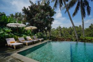 a pool with chairs and umbrellas next to a resort at Pertiwi Bisma 1 in Ubud +63 photos
