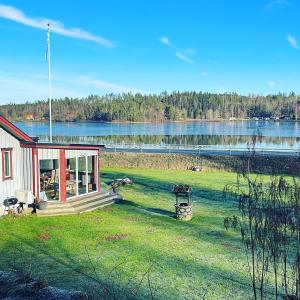a small house in a field next to a lake at Blomstergården in Vilshult